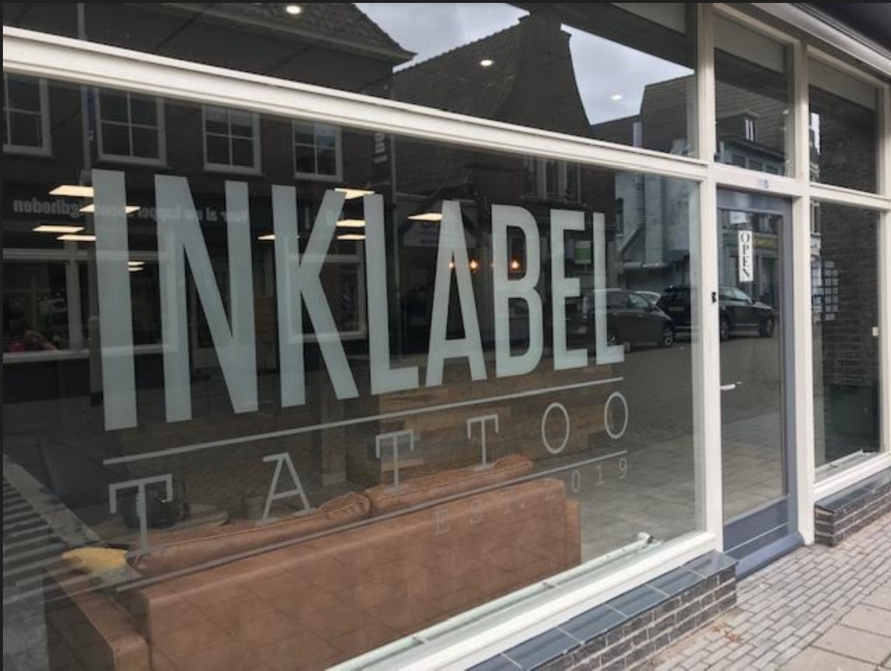 De gevel van Inklabel Tattoo aan de Kade in Roosendaal, met de matglas-belettering INKLABEL TATTOO sinds 2019