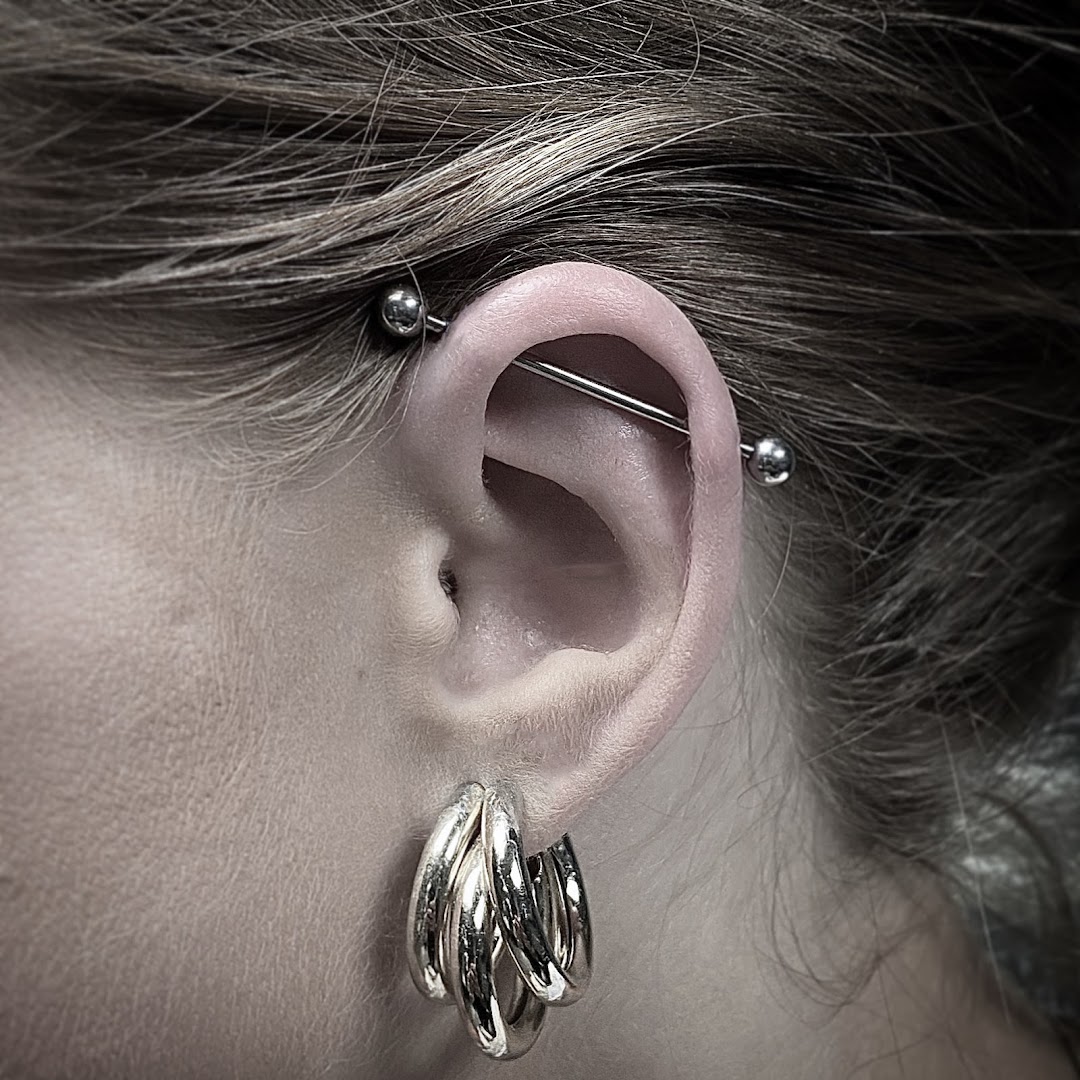 Close-up van een industrial piercing in een oor, gezet bij Inklabel Tattoo