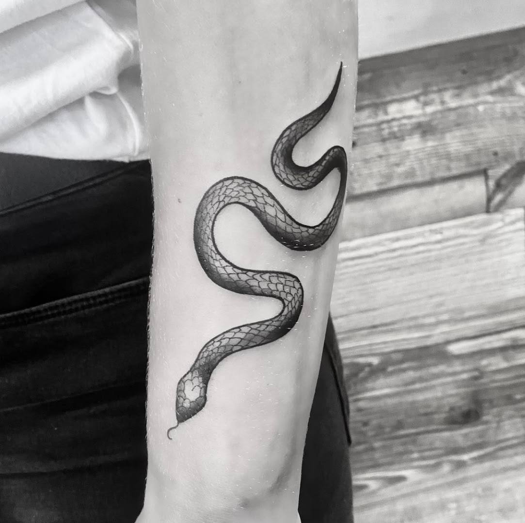 Zwart-wit blackwork tattoo van een slang op een onderarm, gezet bij Inklabel Tattoo